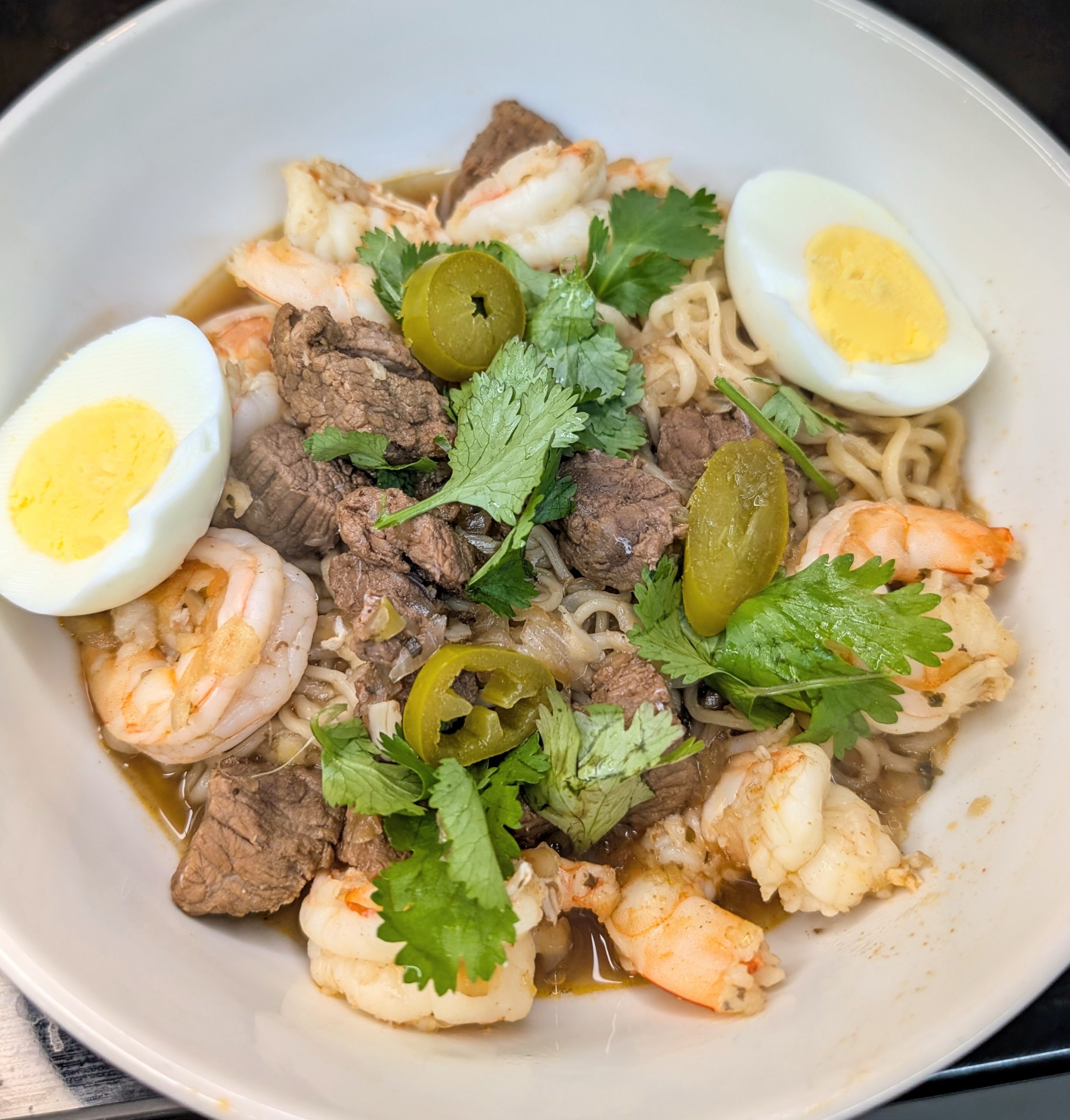 Organic New Orleans shrimp yakamein with beef, ramen noodles, boiled egg, cilantro, and jalapeños in beef bone broth